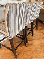 Side view of two stools showing striped fabric and wood legs