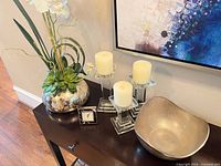 Full set on console table showing vase with flowers, three candle holders with candles, silver bowl and clock