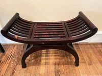 Front view showing slatted seat, curved arms, arched legs, wear spots