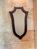 Full view of shield-shaped mirror on wall