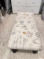 Top view of beige bench showing script print upholstery