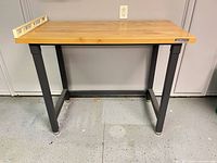 Full view of workbench showing hardwood top, metal legs, adjustable feet