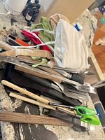 Pile of assorted utensils, oven mitt, lighters, aprons visible