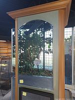 Front view of cabinet showing light wood frame and mirrored doors