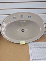 Top view of oval bisque sink showing three faucet holes and drain