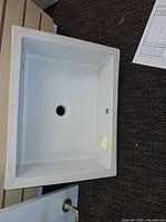 Top view of white rectangular undermount sink showing drain hole and rim