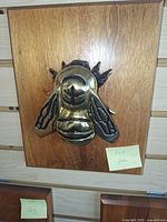 Front view of bee brass knocker on wood plaque