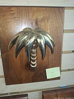 Front view of brass palm tree door knocker on wood plaque