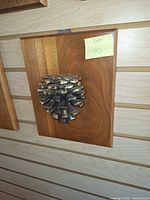 Front view of brass pine cone door knocker on wood board
