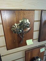 Front view of brass floral door knocker on wood plaque