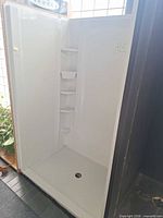 Front view of assembled white corner shower with base and shelves
