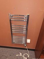 Front view of mounted chrome towel warmer with power cord