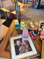 Overview showing framed print, coin bank, Minions, whoopee cushion, decorative plate and part of dolls