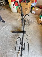 Full view of black steel hitch-mount 2-bike rack showing wheel trays and vertical support