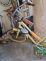 Side view of yellow cruiser bicycle showing frame, handlebars, wheels