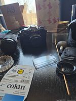 Camera body with mounted 50 mm lens, telephoto lens, filters, accessories