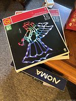 stack of boxed LED angel silhouette lights and additional boxed light items