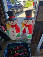 Two plastic snowmen, white wire deer, bin with multicolour stake lights, Canvas box visible