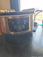 Front view showing Hamilton Beach branding, stainless body, digital panel, glass lid