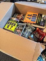 Box containing multiple J.D. Robb novels, top copies Brotherhood in Death, Seduction in Death etc.