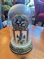 Front view of Disney glass dome clock showing dial, pillars and pendulum