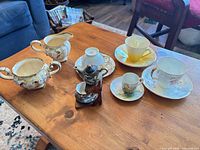 Group shot of sugar bowl, creamer, four teacup sets, miniature teapot