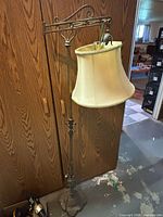 Full view of ornate cast iron floor lamp with cream fabric shade