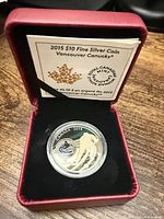 Coin in capsule inside presentation box with certificate visible