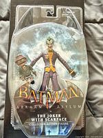 Front view of sealed Batman: Arkham Asylum Joker figure packaging showing figure and Scarface accessory