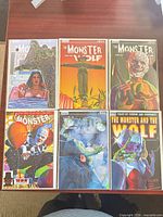 Six variant covers of The Monster and the Wolf #1 displayed on tabletop