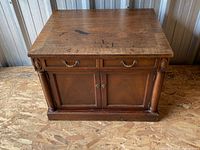 Front view of closed end table showing drawers, doors, hardware and wear on top