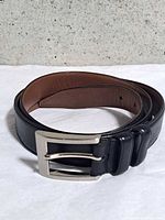 Belt coiled showing black outer, brown inner, buckle and keepers