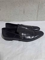 Outer side profile of both loafers showing leather finish and buckle