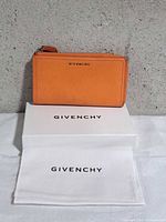 Front view of orange Givenchy wallet on branded box and dust cloth