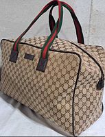 Front angled view showing GG canvas, web handles, zip top