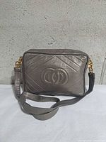 Front view showing quilted pattern, embossed oval motif, strap attached