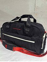 Front view showing Porsche logo, front zip pocket, shoulder strap