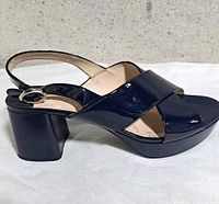 Side view of a single navy patent leather Prada slingback sandal showing block heel and crossover vamp