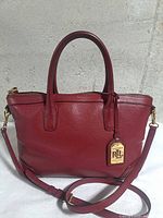 Front view of red pebbled leather Ralph Lauren handbag with logo tag and strap