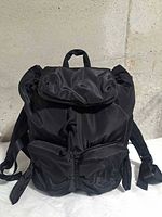 Front view of black nylon Joy Rider backpack showing flap, rope drawstring, front pockets