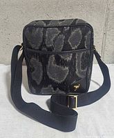 Front view showing leopard pattern, front pocket, Orb emblem, strap and buckle