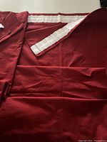 Folded red curtain panel showing full fabric and header tape