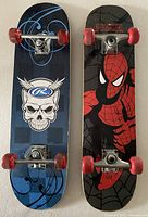 Bottom view of both skateboards showing graphics, trucks, wheels