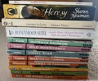 Stack of twelve vintage romance paperbacks side view showing spines and titles.