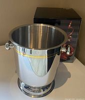 Bucket front view showing reflective stainless finish, gold band and handles