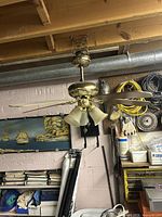 Overall view of brass ceiling fan with four glass shades and wood blades hung from ceiling