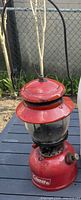 Front view of red Coleman lantern showing globe and control knob
