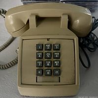 Front view of beige ITT push-button telephone with handset on cradle