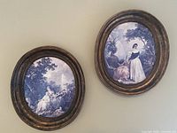Both oval framed prints side by side on wall
