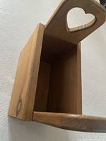 Angled view showing interior cavity, one heart-cut handle, and grain